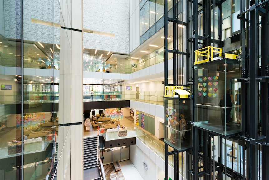 Two lifts run in the glass foyer of a cancer treatment center