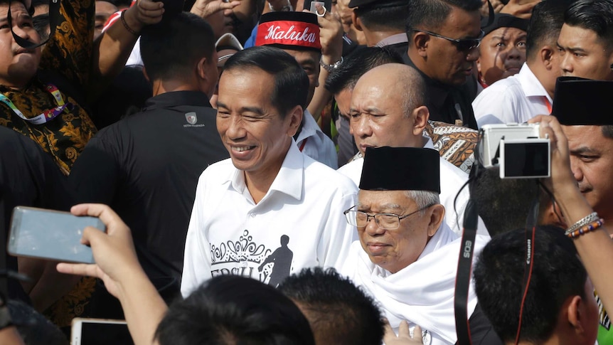 Indonesian President Joko "Jokowi" Widodo, center left, and his running mate Ma'ruf Amin, center right, greet their supporters