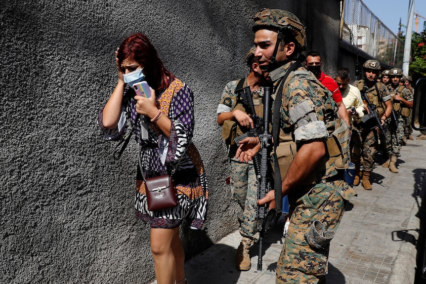 Lebanese army special forces soldiers protect teachers as they flee their school.