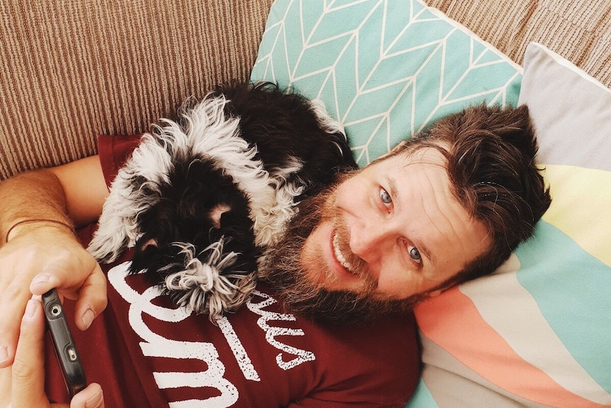 Peppa lays across Travis on the couch to depict surviving the week with a new pet puppy.