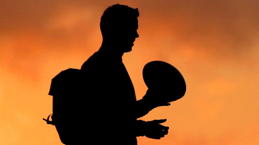 Rugby player silhouetted against sunset