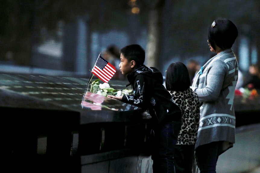 People look at names of victims on the National 9/11 Memorial.