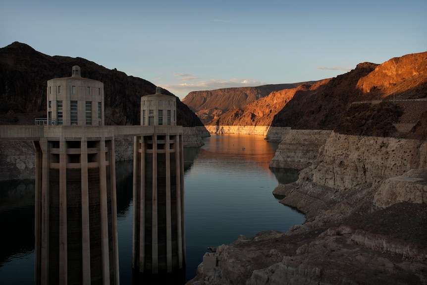 A bathtub ring of light minerals shows the high water line of a drying lake. Sunlight only in background on mountains. 