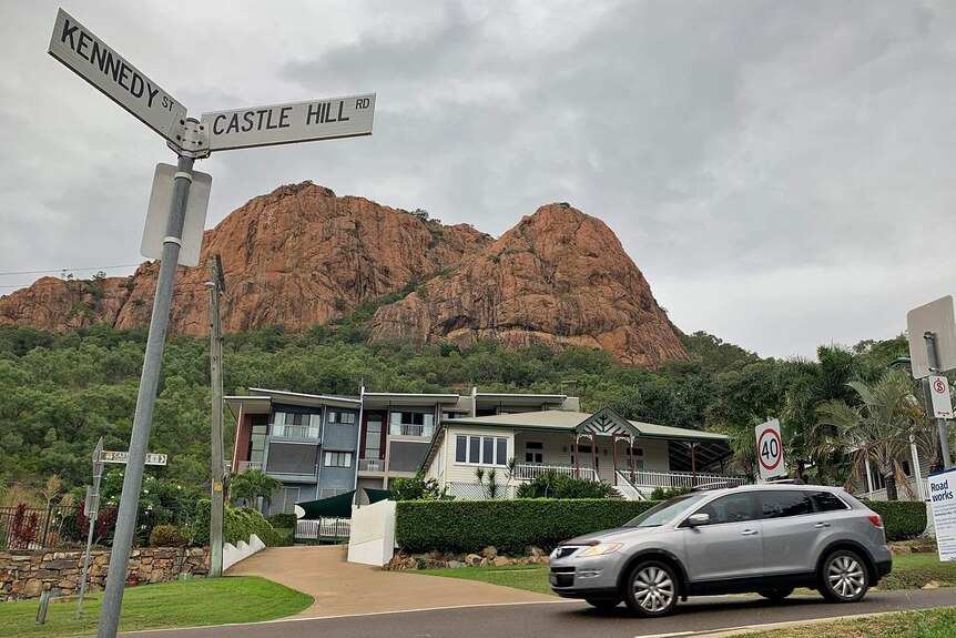 A car drives on Castle Hill Road which is in front of Townsville's monolith Castle Hill
