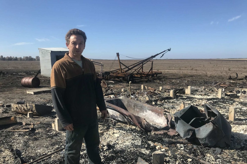 Adam Parker stands in front of the charred remains of his farmhouse.
