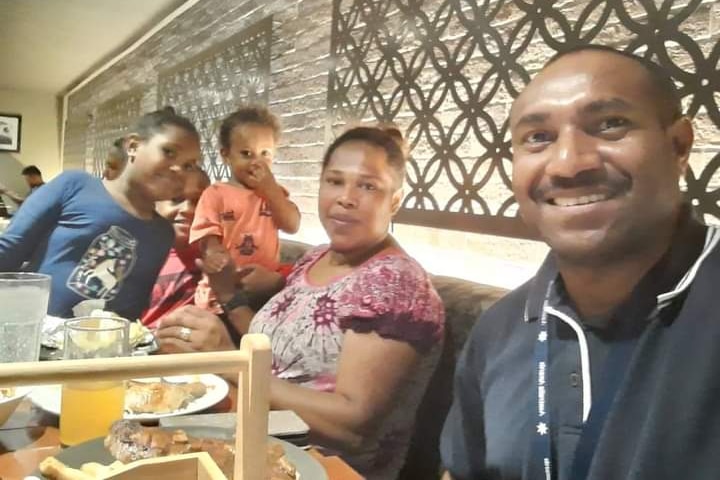 Randall, Sophie and the three children sitting at a table together smiling.