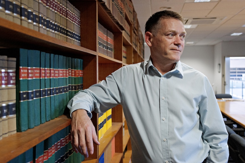 Middle aged man standing in front of bookshelves
