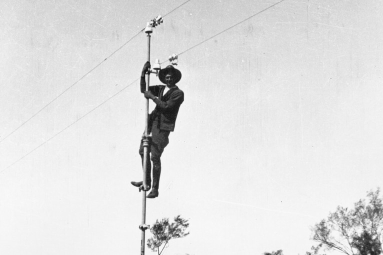 Bob Carew up a pole of the Overland Telegraph Line.
