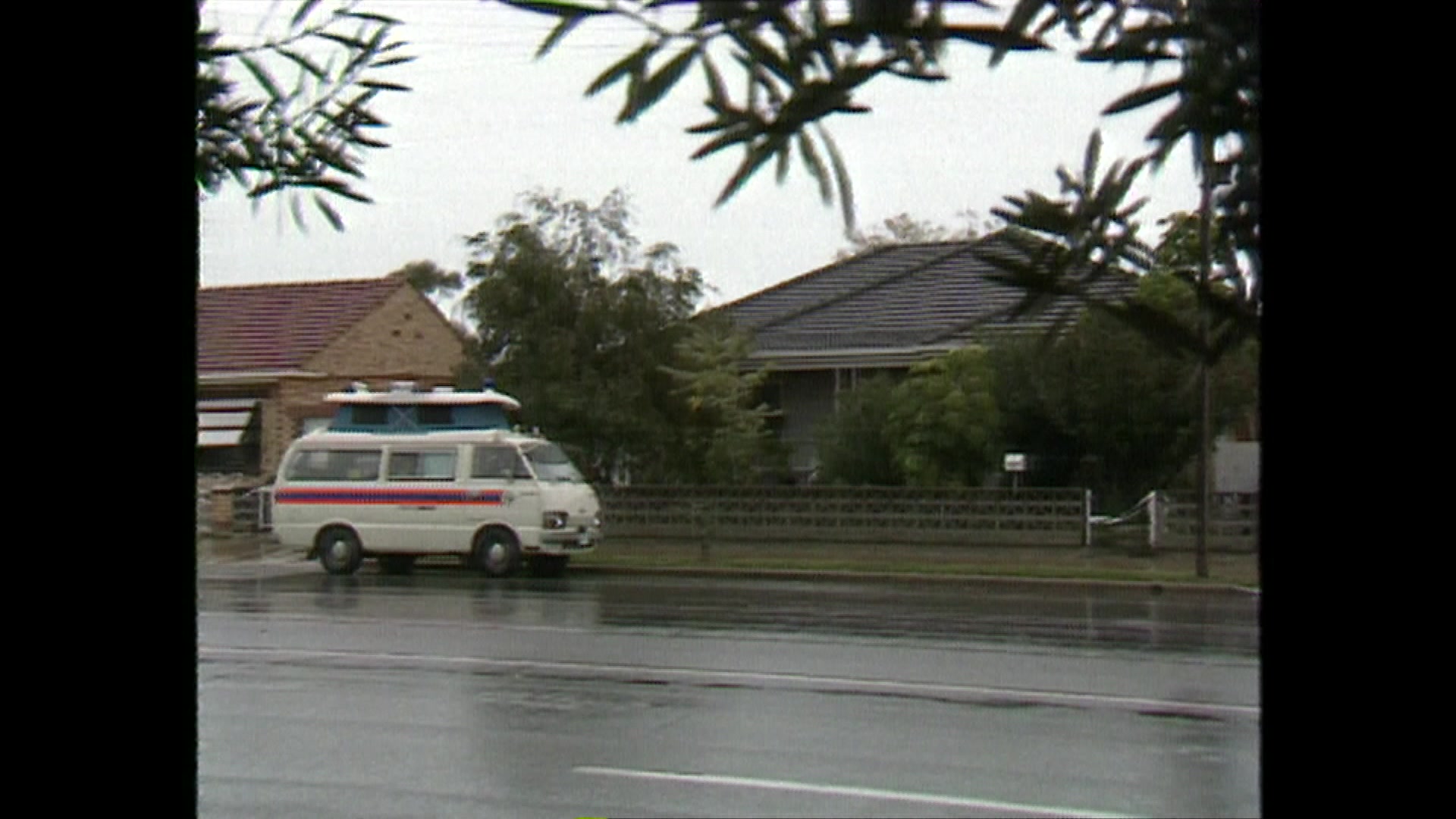 A view of a home with a white van outside on a wet street.
