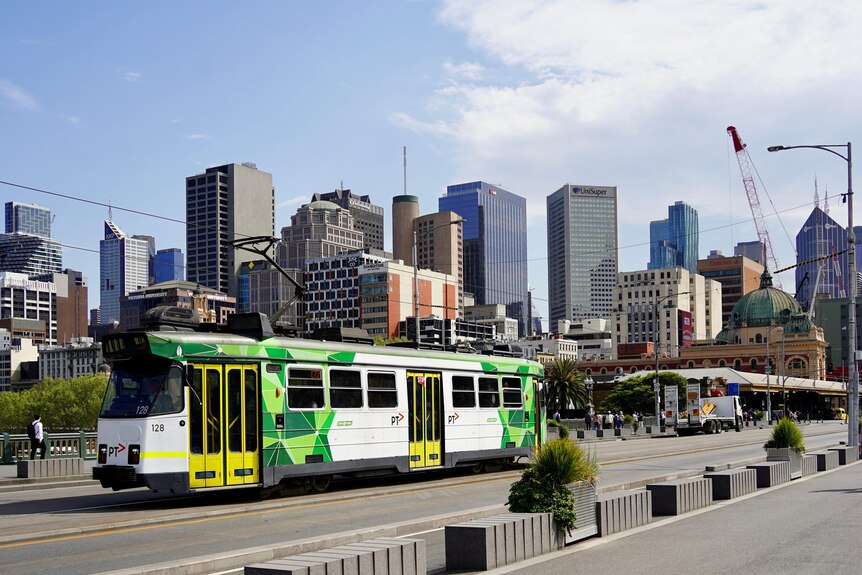 Princes Bridge leading into Melbourne's CBD on a sunny day with a green and white tram passing on September 19, 2023