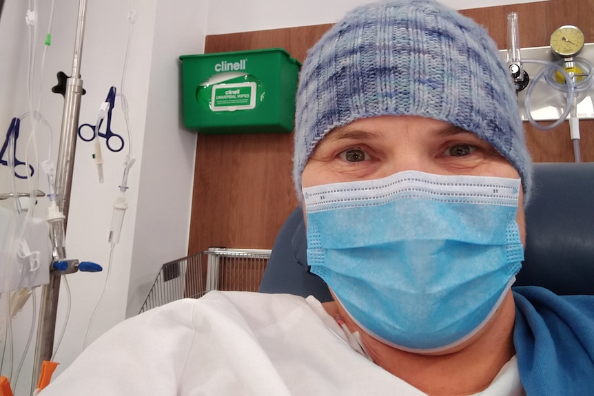 A woman wearing a blue face mask and a beanie in a hospital.