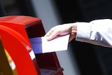 A man puts a letter in an Australia Post post box.
