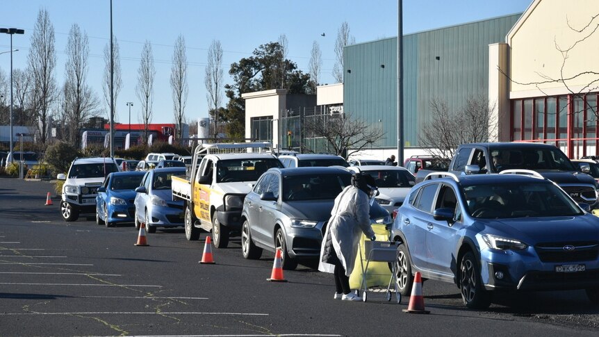 rows of cars at a drive through testing clinic in a carpark
