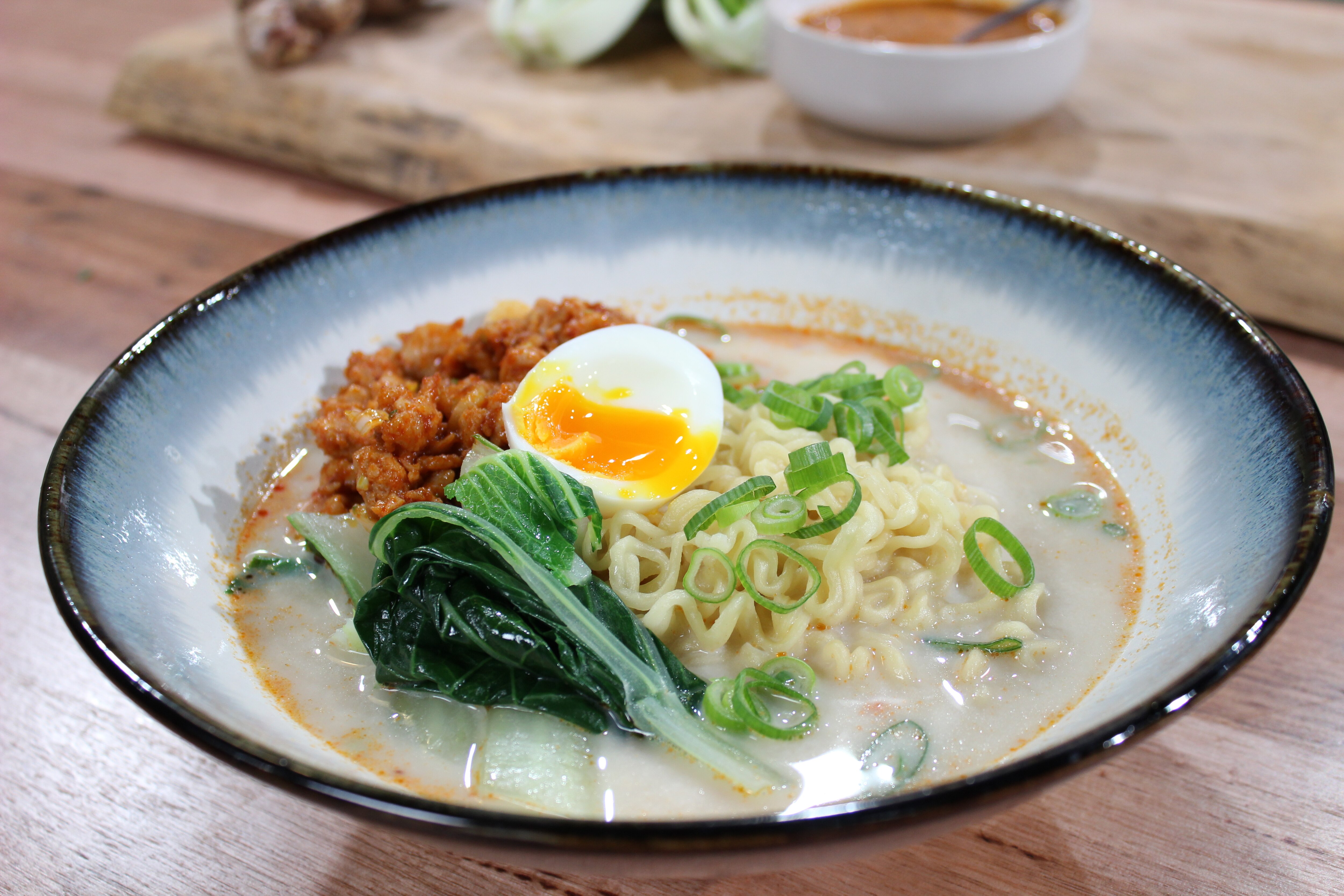 Finished dish of a bowl of ramen in serving bowl on bench