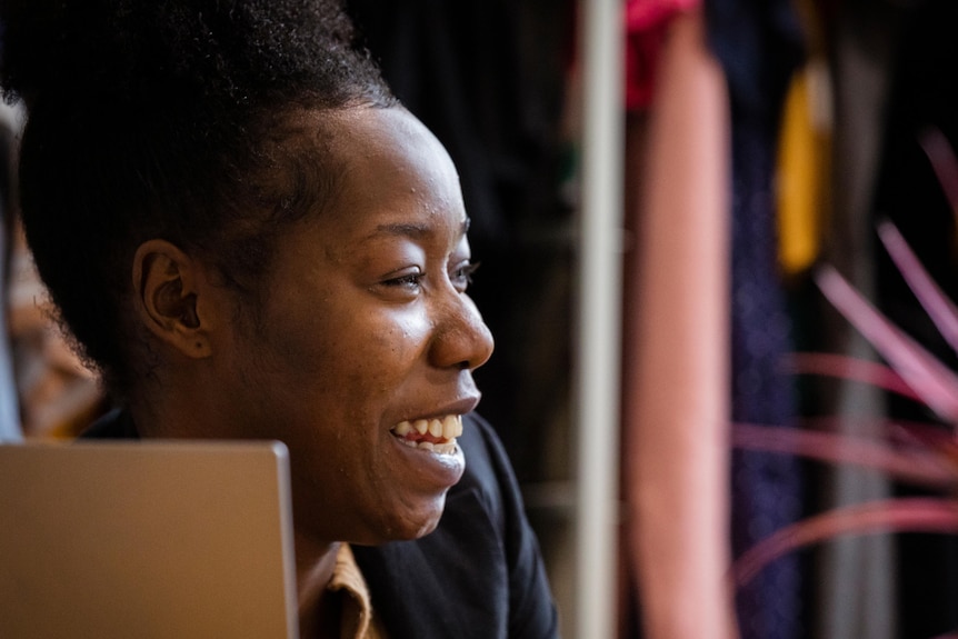 A close up photo of a young woman's face while she is laughing at something.