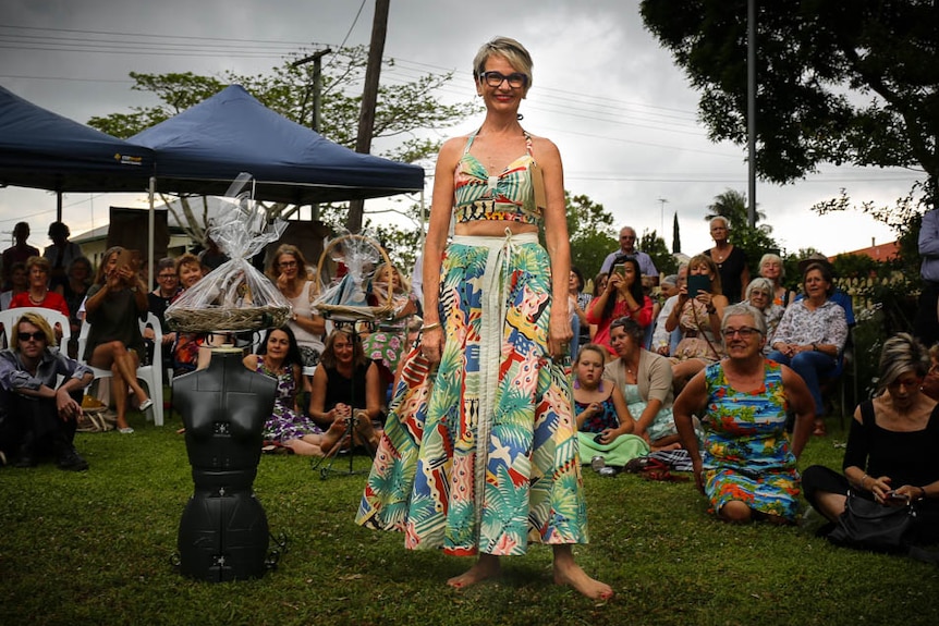 Model wearing brightly coloured top and skirt, standing in a crowd