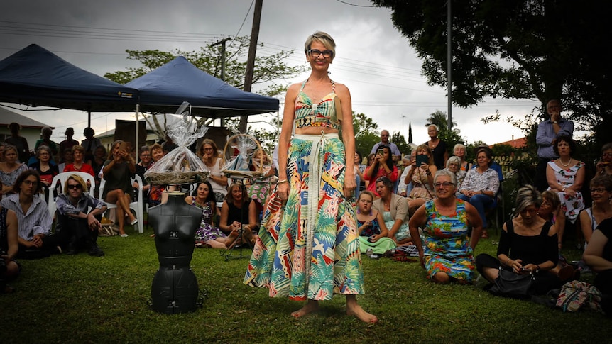 Model wearing brightly coloured top and skirt, standing in a crowd
