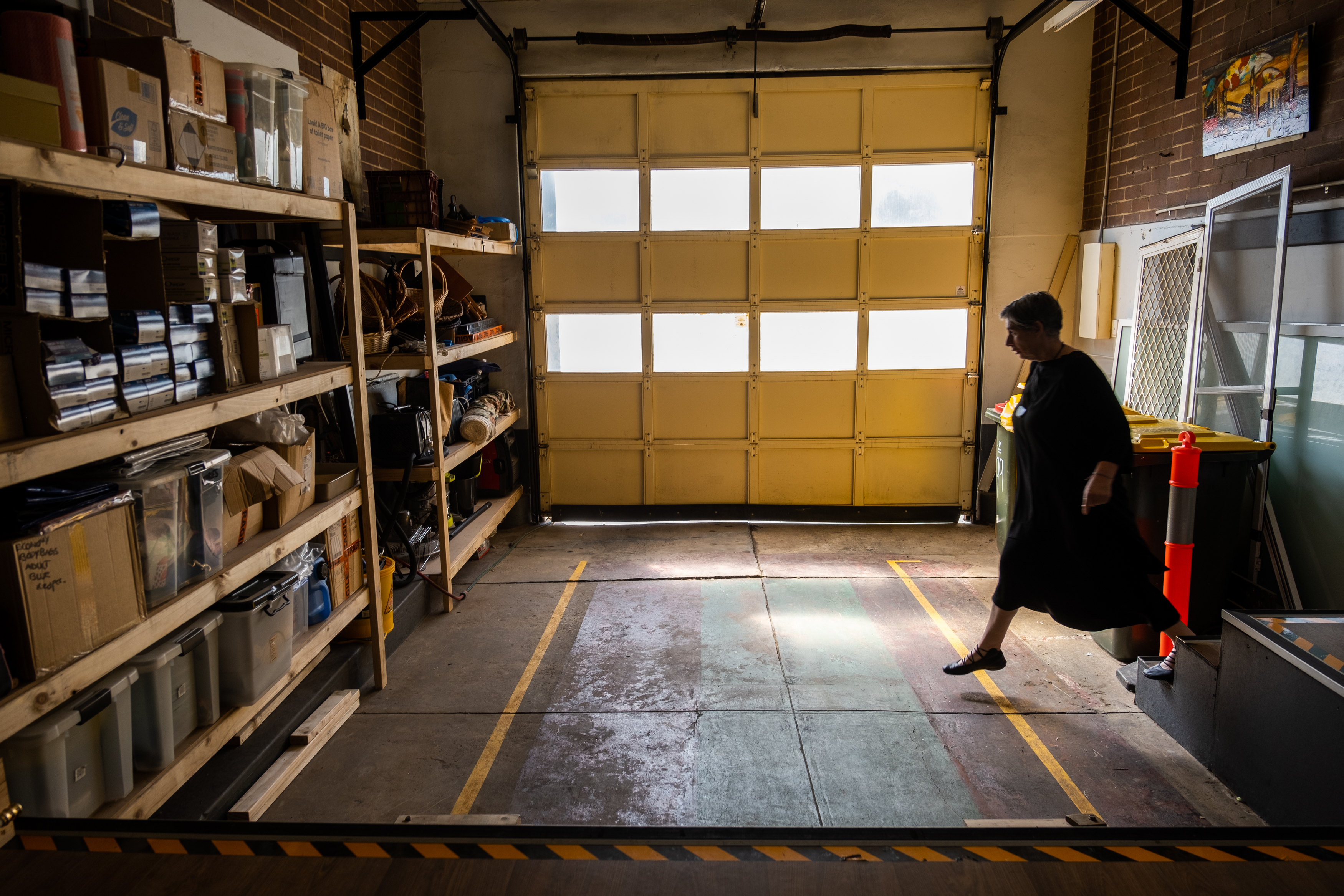 Wide shot of a woman walking through a dimly lit garage.