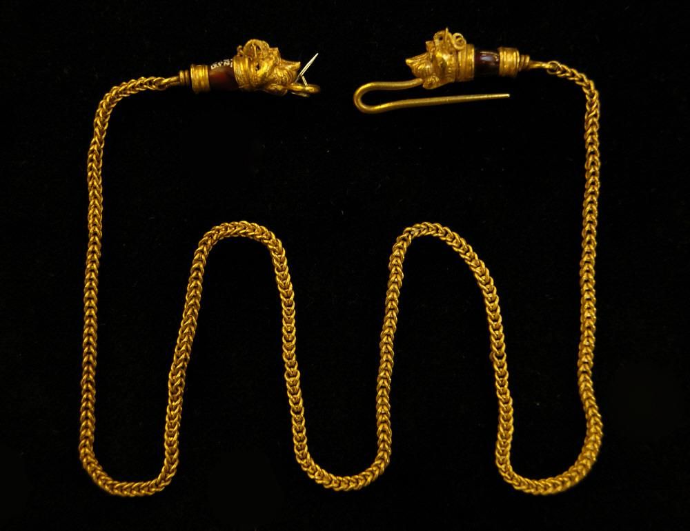 An ancient Greek gold chain necklace against a black background
