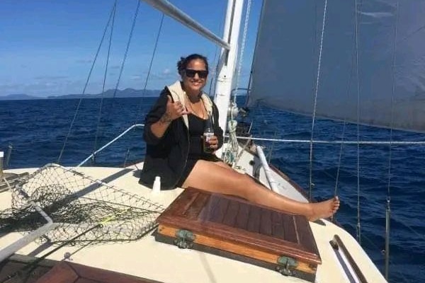 woman holding a beer bottle on a sailing boat in a scenic location.