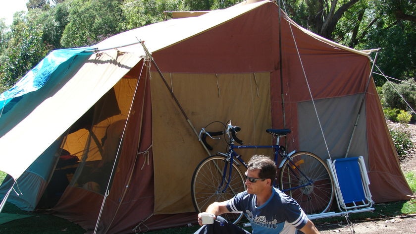 Man sitting in front of a tent.