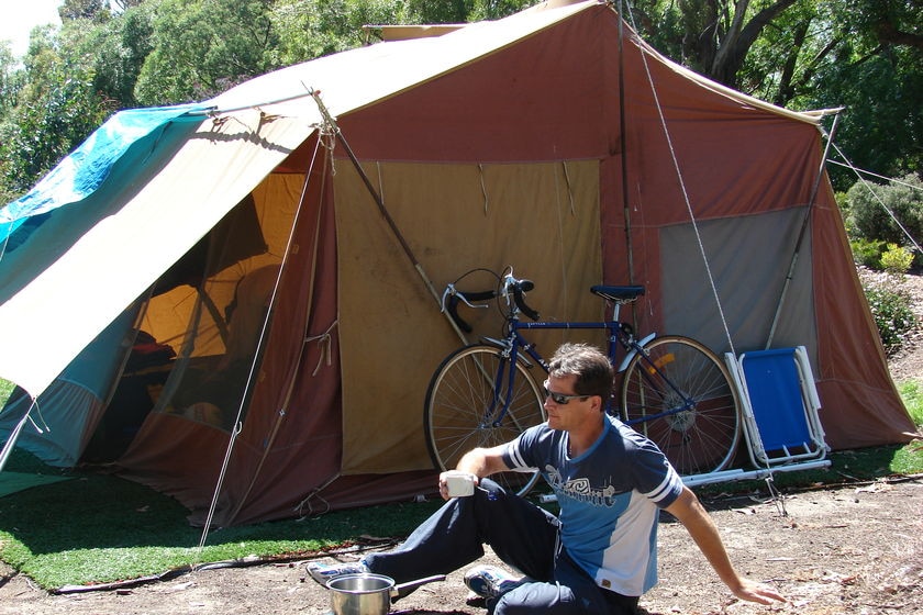 Man sitting in front of a tent.