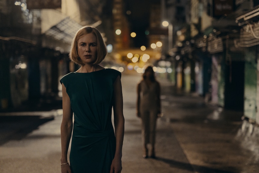 A TV still of Nicole Kidman standing on a Hong Kong street with a fearful expression. A shadowy figure is behind her.