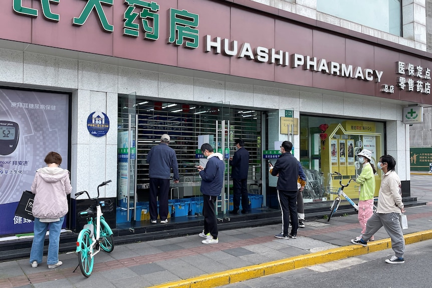 Un groupe de personnes attend devant une pharmacie de Shanghai