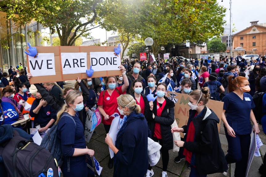 A large group of people and a group holding a sign which says: "We are done"