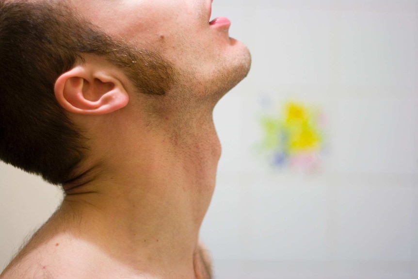 A man tilts his head to the ceiling as he gargles water.