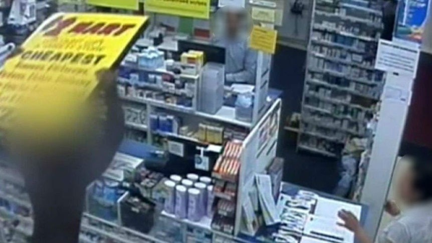 A man holds a sign over his head inside a chemist