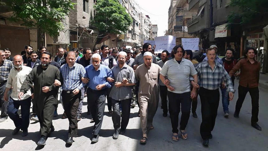 Men link arms in protests against rebel infighting near Damascus.