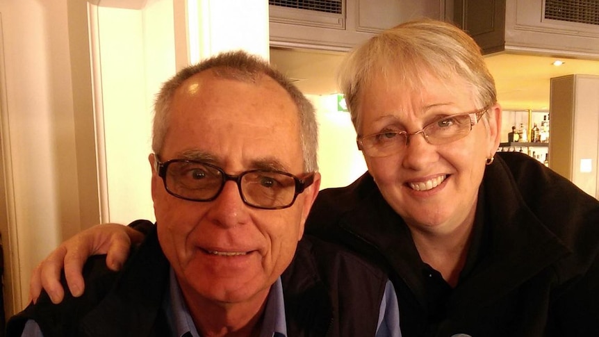 A man with glasses and a woman with short hair, smiling.