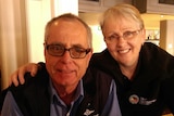 A man with glasses and a woman with short hair, smiling.