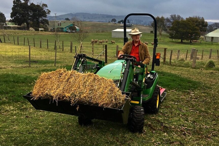 Kim Peart drives a tractor on his rural property.