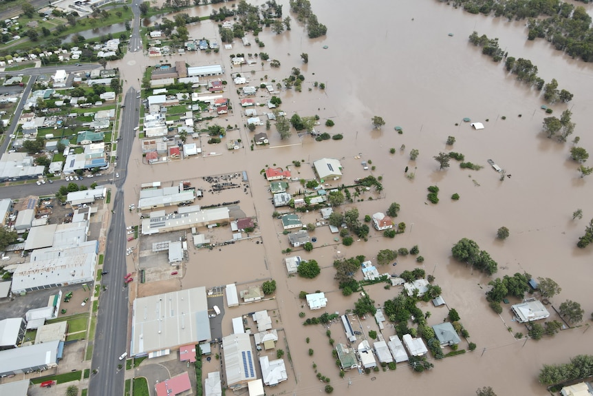 Houses and road inundated by brown floodwaters.