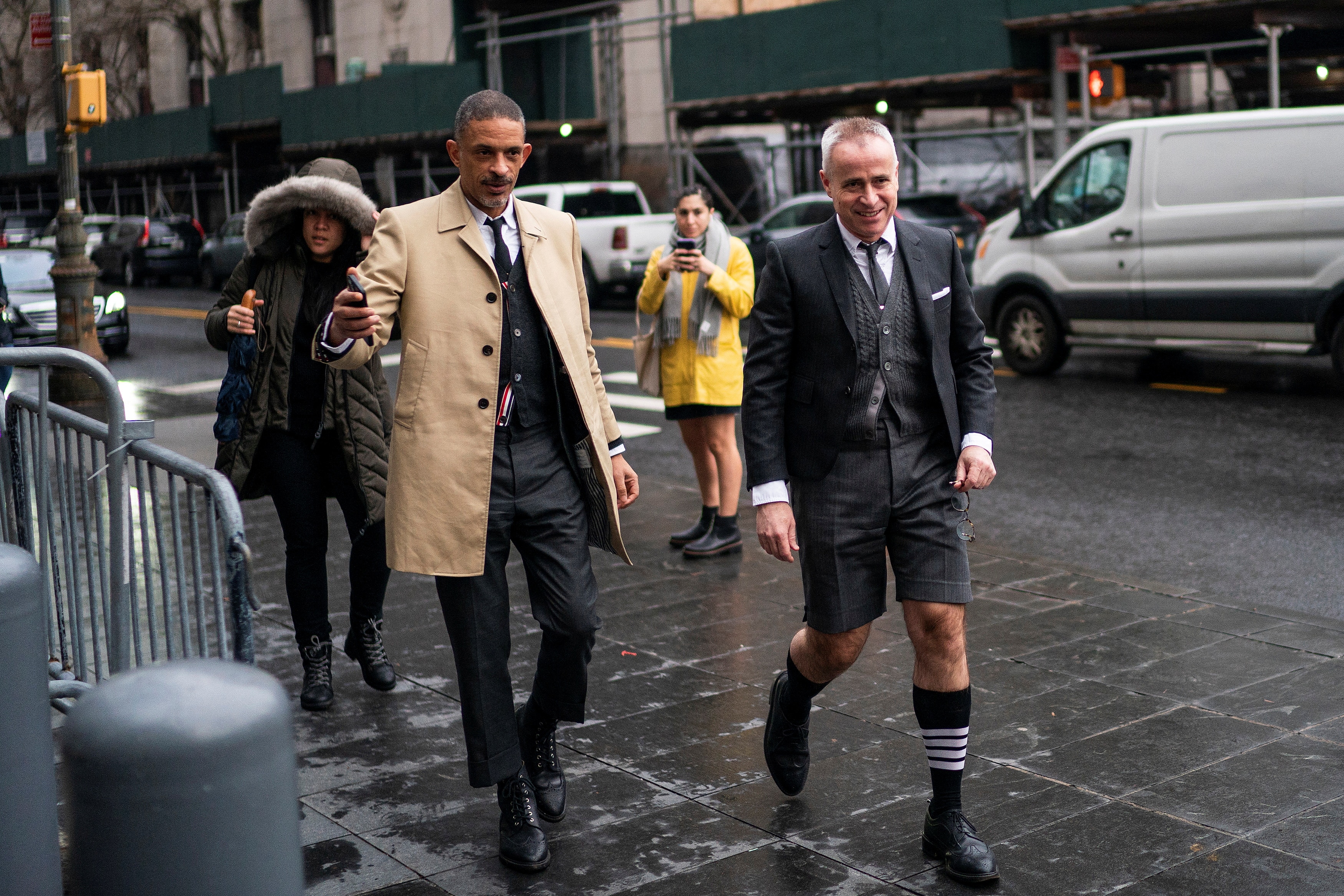 Thom Browne walking with another man wearing socks with a four stripe design.