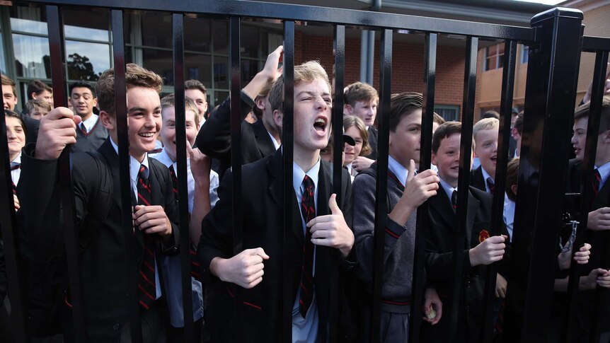 Students hold the fence and cheer Bill Shorten, who is not in the photograph