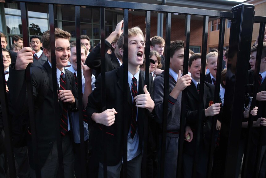 Students hold the fence and cheer Bill Shorten, who is not in the photograph