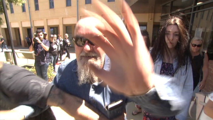 An enraged man wearing a blue shirt and sunglasses.