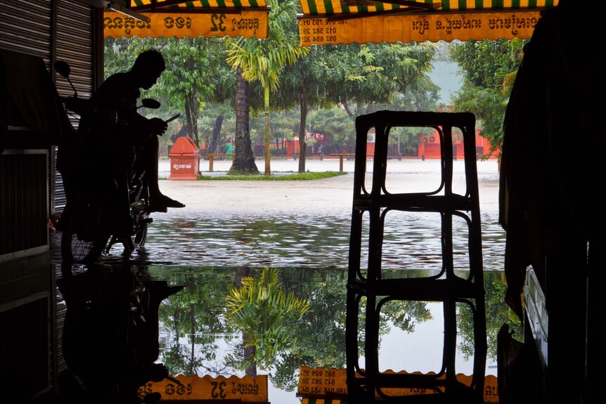 A man sits undercover in Siem Reap as floodwaters rise in late September, 2011.