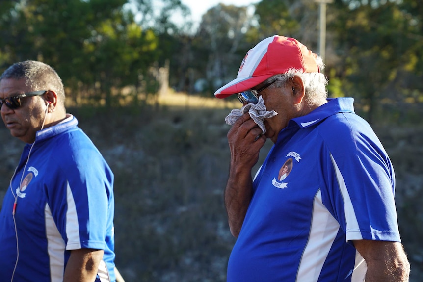 Buddy's family gather by the river near the rail bridge in Kempsey, wearing footy shirts with his portrait printed on the back.