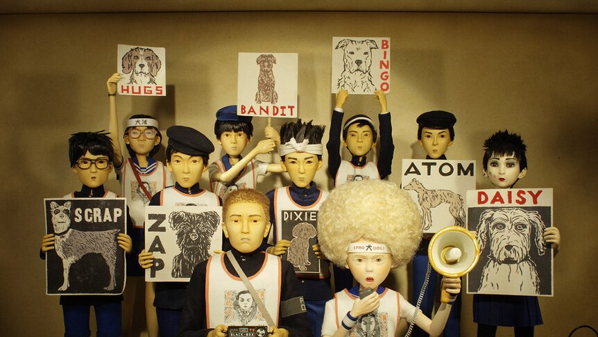 Colour still of student animal activists holding up posters of dogs in a protest in stop-motion animation Isle of Dogs.