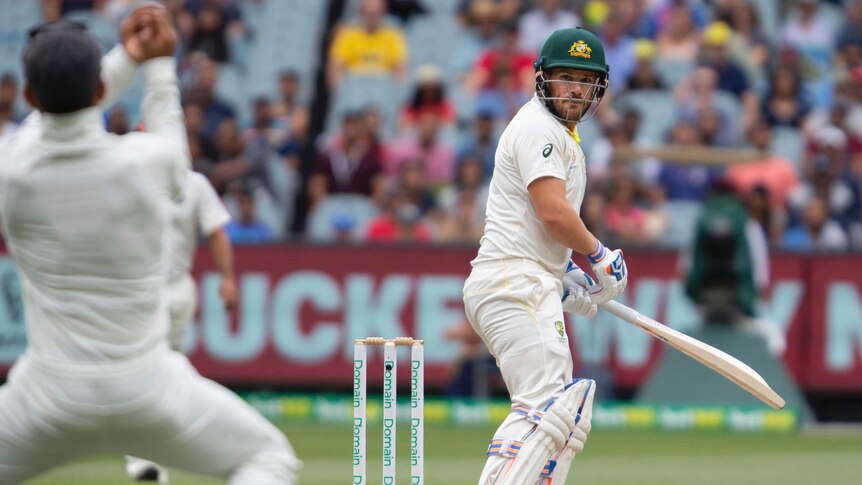 Australia batsman Aaron Finch looks over his shoulder as India captain Virat Kohli, blurred in the foreground, catches him out.