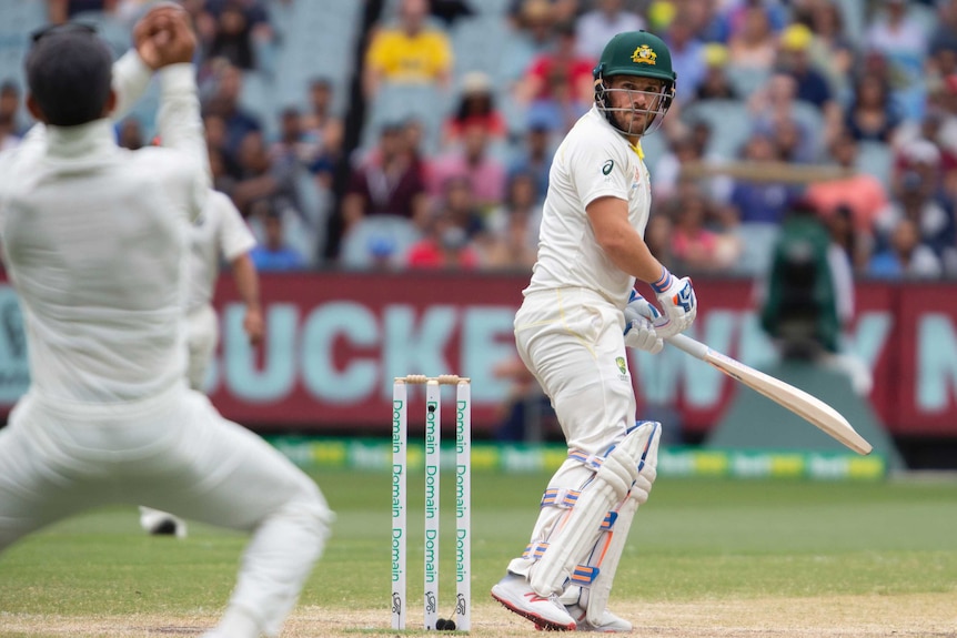 Australia batsman Aaron Finch looks over his shoulder as India captain Virat Kohli, blurred in the foreground, catches him out.