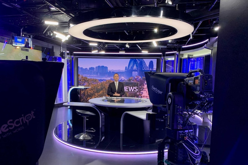 Wide shot of O'Brien in studio surrounded by cameras and lights.