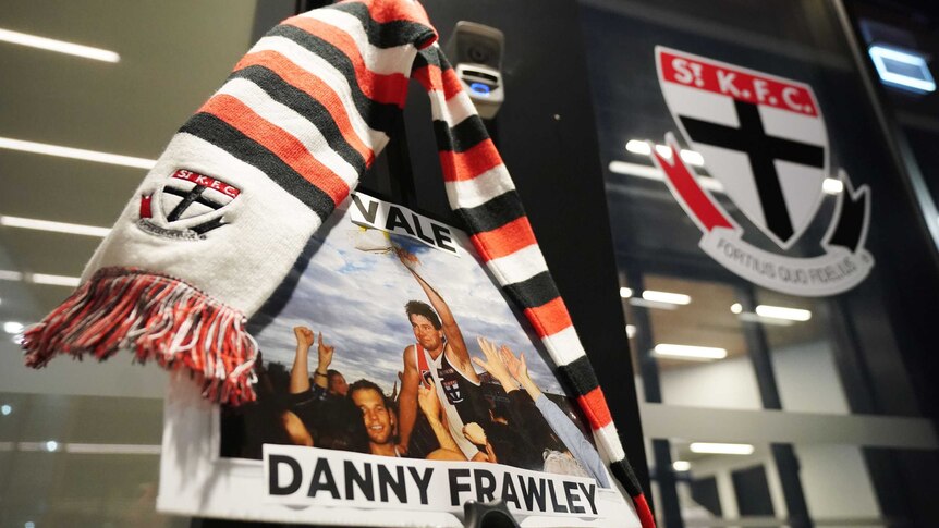 A picture with the words "Vale Danny Frawley" is placed on a door with a St Kilda scarf on it.