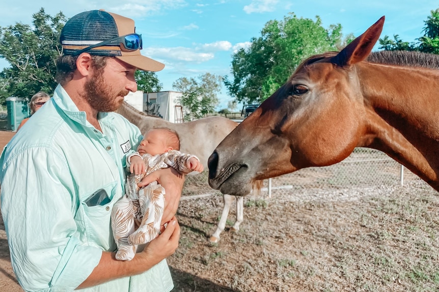 A father introduces his new child to a horse. 