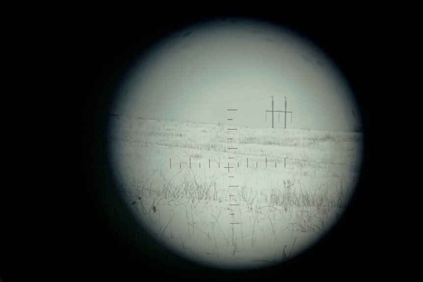 A periscope lens focuses on a white empty landscape, with only electricity poles breaking up the horizon
