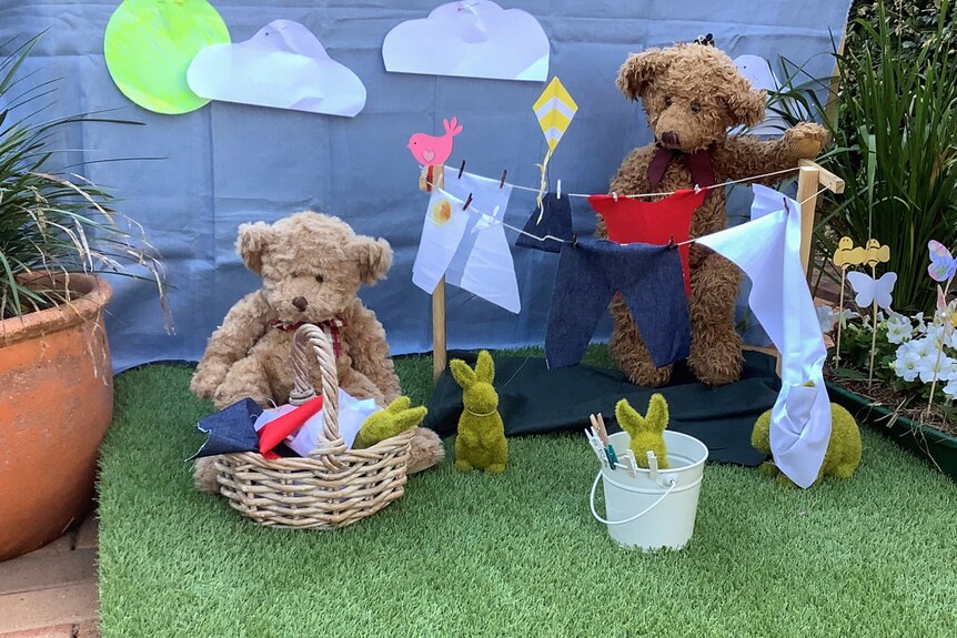 Two teddy bears hang out washing with green bunnies.